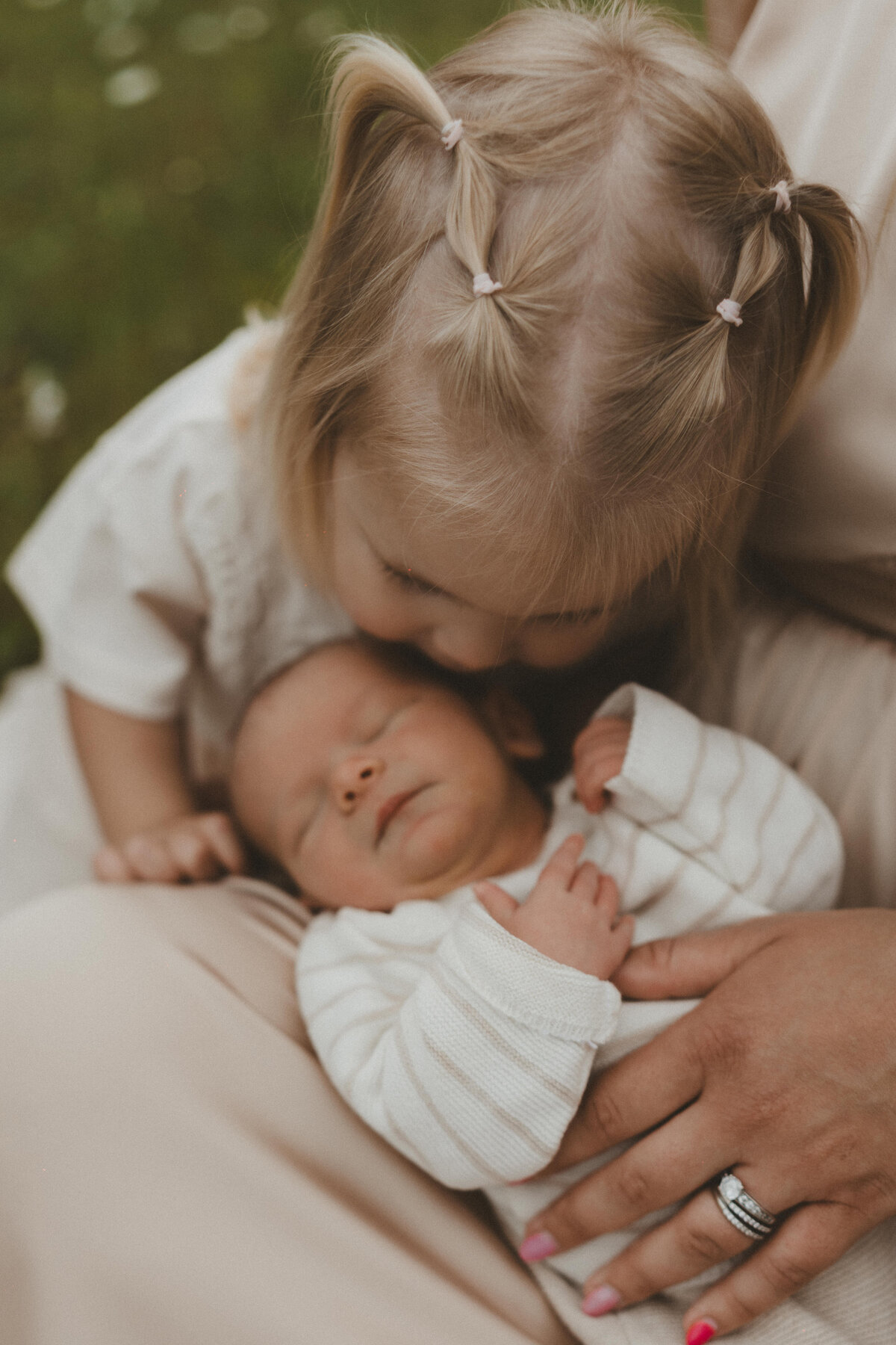 Foto van zusje die haar baby broertje een kusje geeft.