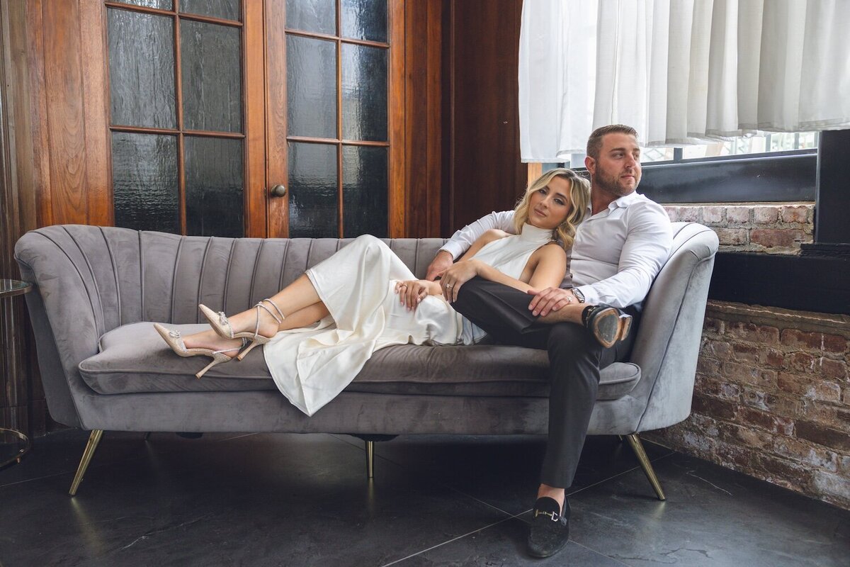Bride lounging across vintage sofa with groom at Felina.