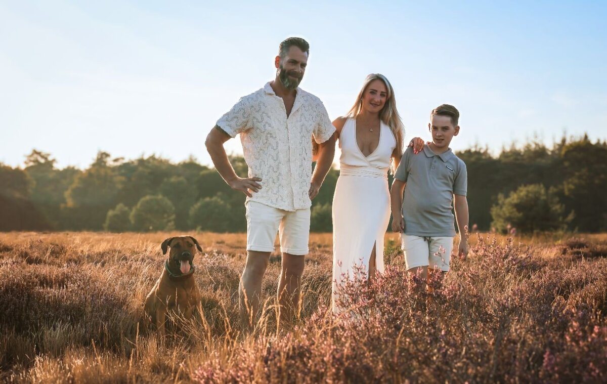 Een liefdevol gezin geniet samen van de 'golden hour' in de natuur, met hun hond aan hun zijde
