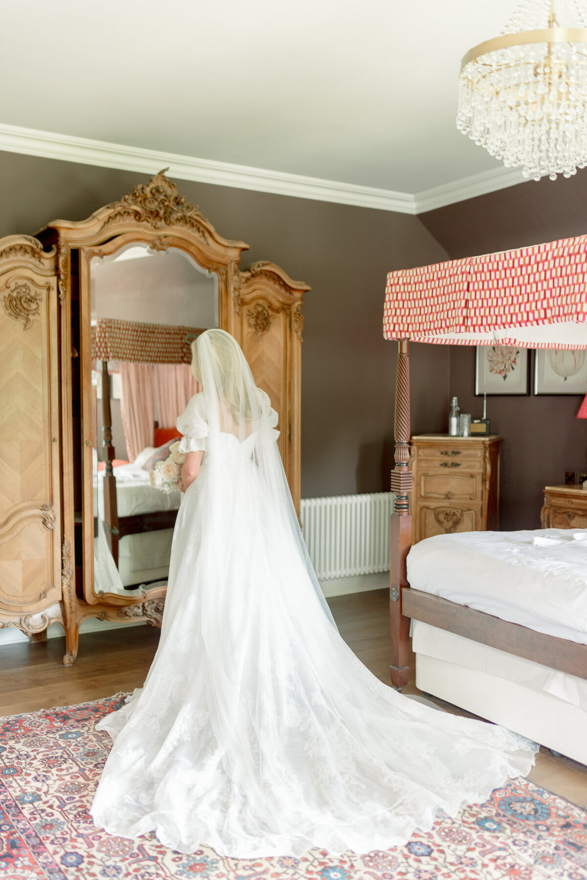 Beautiful morning bride portrait of Bride from behind in patterned soft silk wedding gown with puff sleeve and cathedral length veil, standing in Bridal Suite of Cromlix House, Scotland.