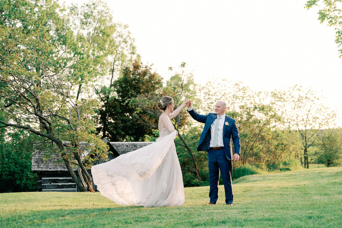 groom twirling bride by the hand in lush green natural scenery