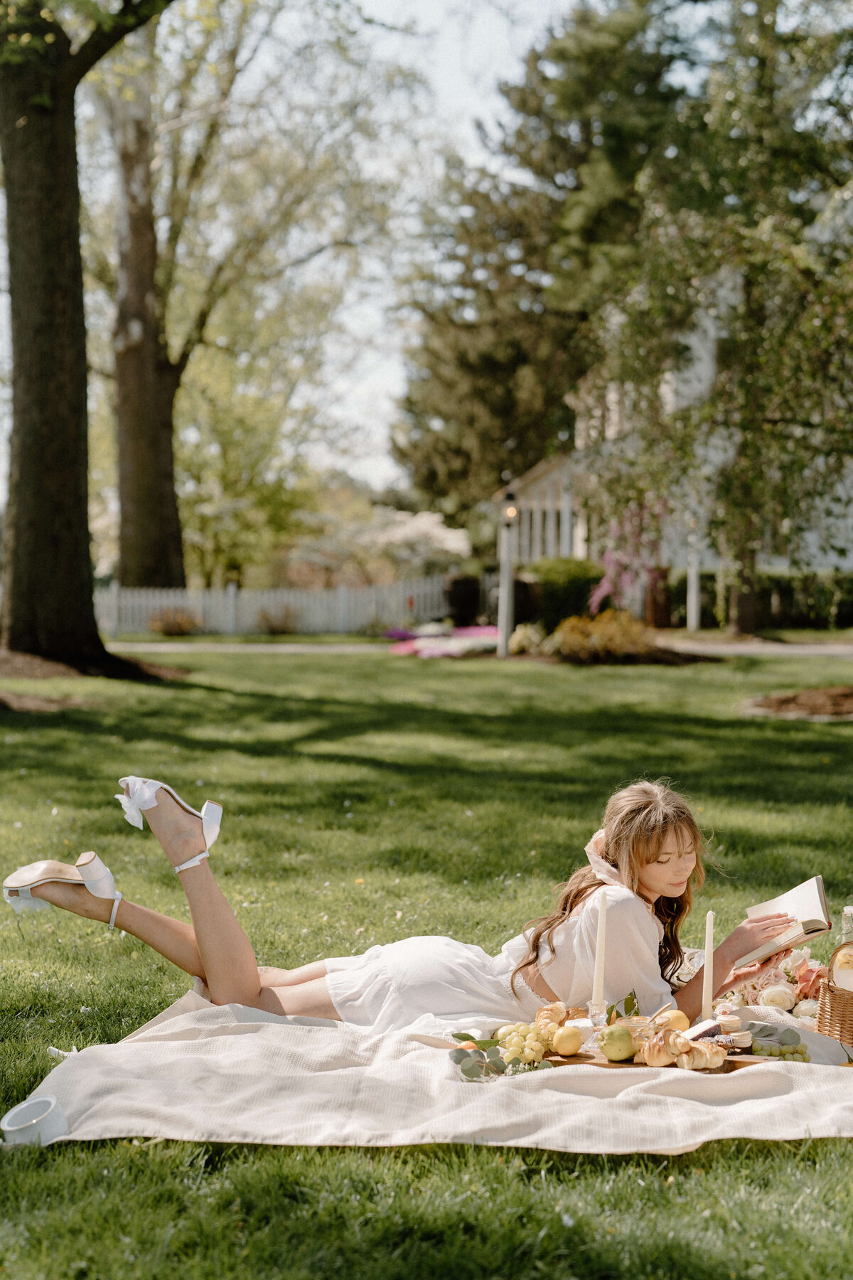 bride lying on a white blanket readying at white chimneys estate, Lancaster, PA