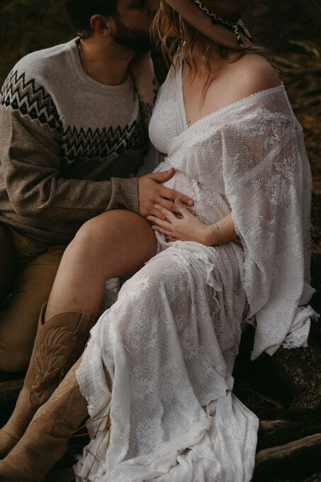 Gros plan sur le ventre rond d'une future maman avec la main de son compagnon posée dessus. Séance photo grossesse en Bretagne.