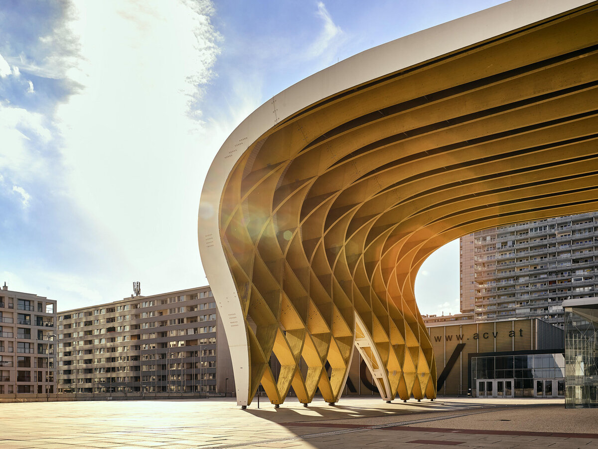 Architekturfotografie des Austria Center Vienna mit markanter Holzkonstruktion im Abendlicht – starke Linienführung, geometrische Formen und warme Lichtstimmung, aufgenommen von Atelier Schulte in Wien.