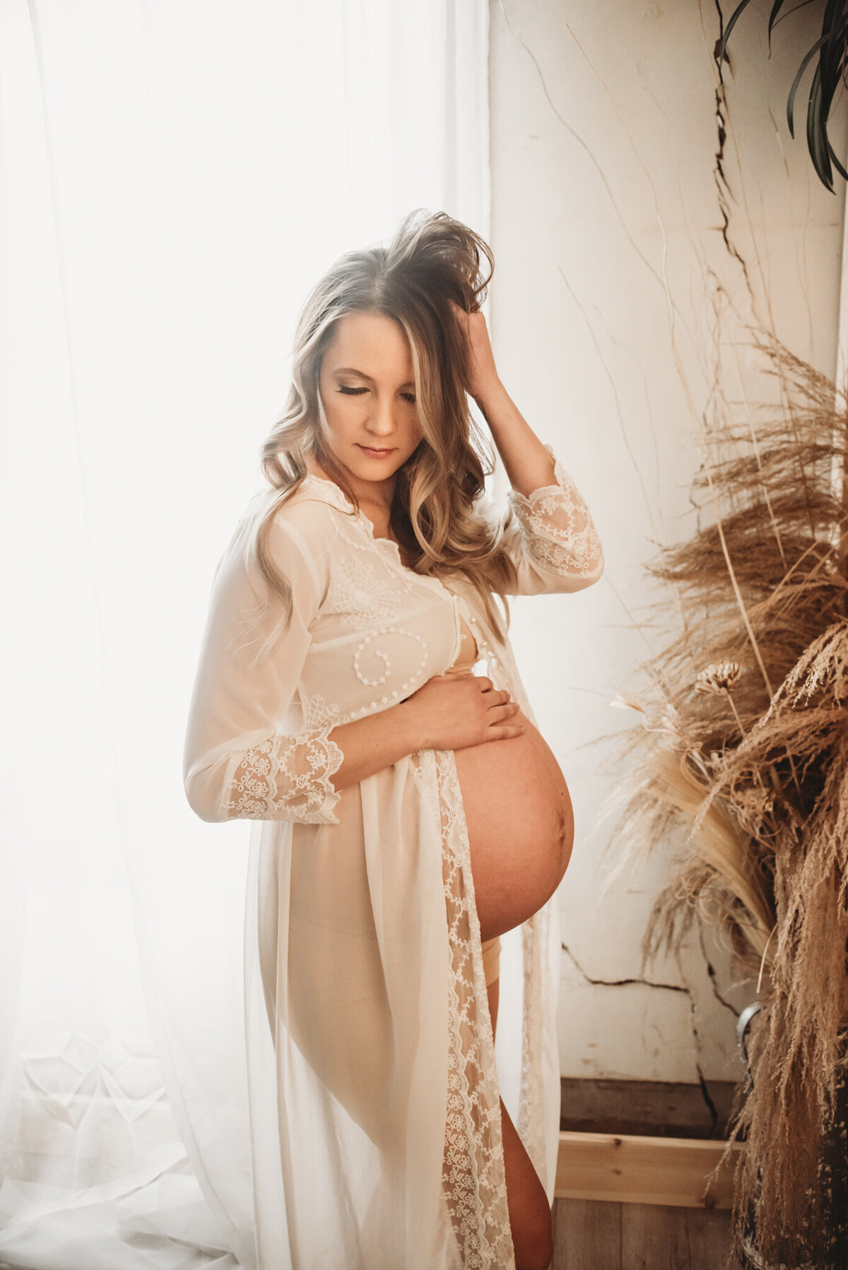 A momma embraces her twin bump during an intimate maternity session in the downtown bismarck studio with Nikii PIx Photography