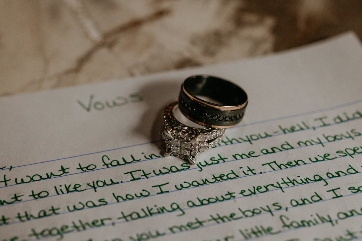 two wedding rings stacked on top of hand written vows