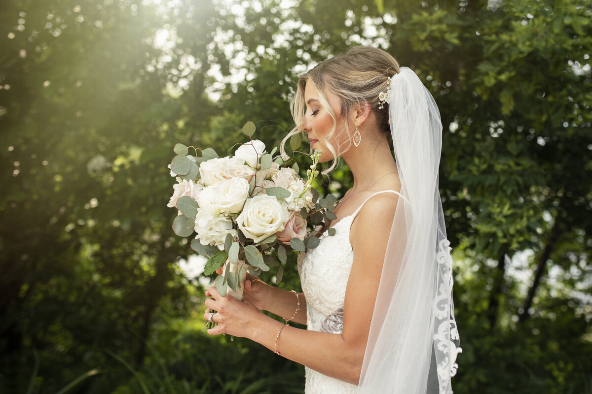 bride with blond hair smelling her flower bouquet on her wedding day