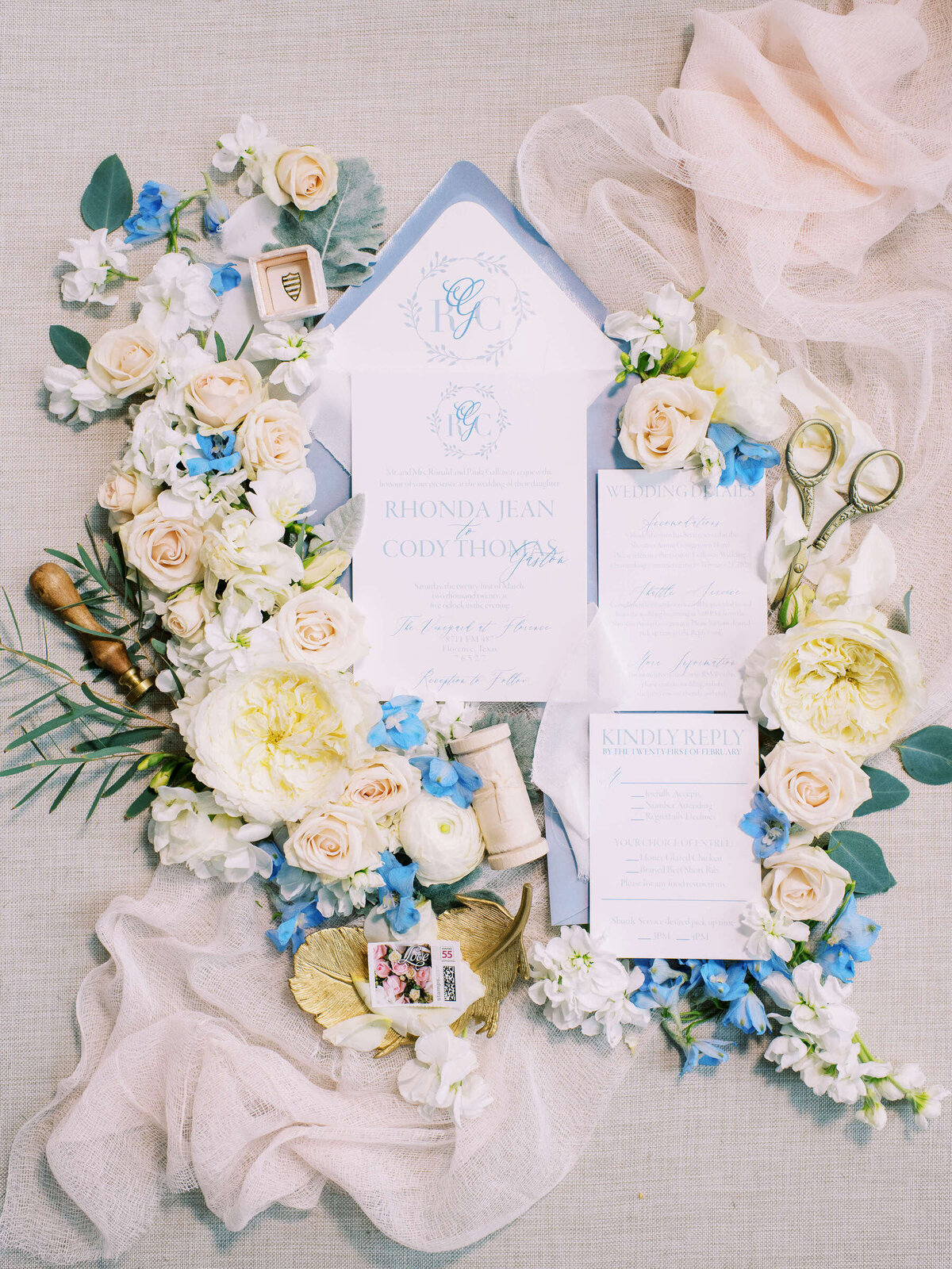 Flatlay of wedding invitation suite with light blue and blush spring florals