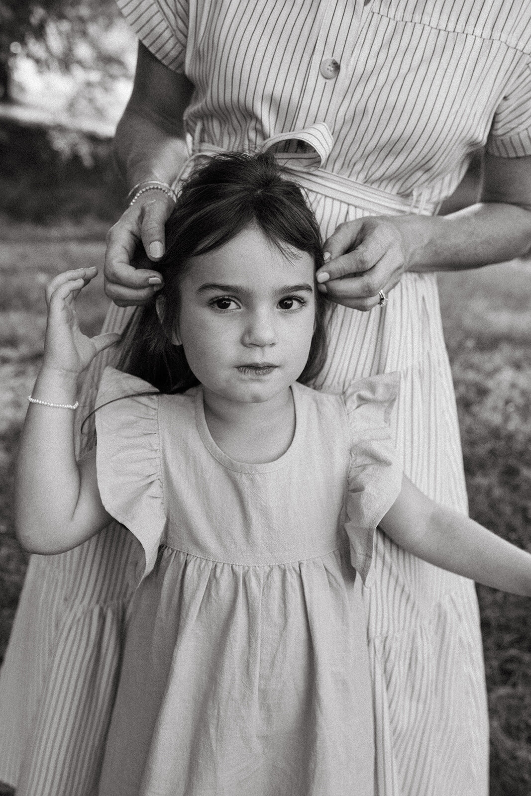 Mother gently playing with her toddler daughter’s hair during a lifestyle family photo session

