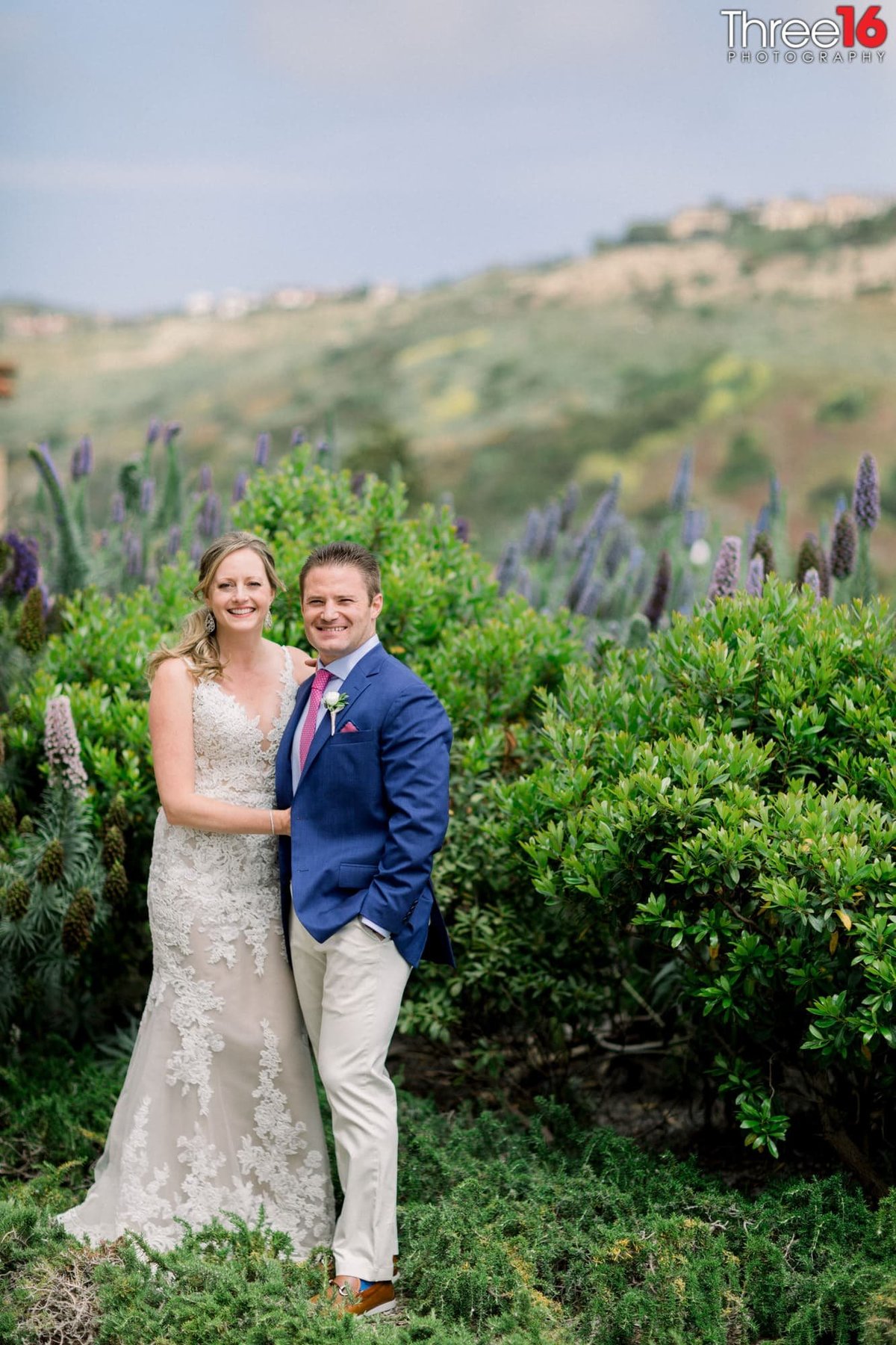 Bride and Groom pose for photos in front of the green bushes at the park at Crystal Cove State Beach
