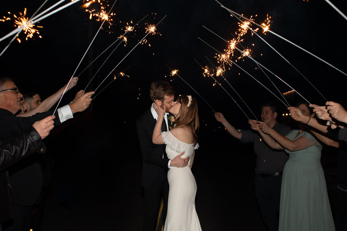 Bride and groom kissing with sparklers around them