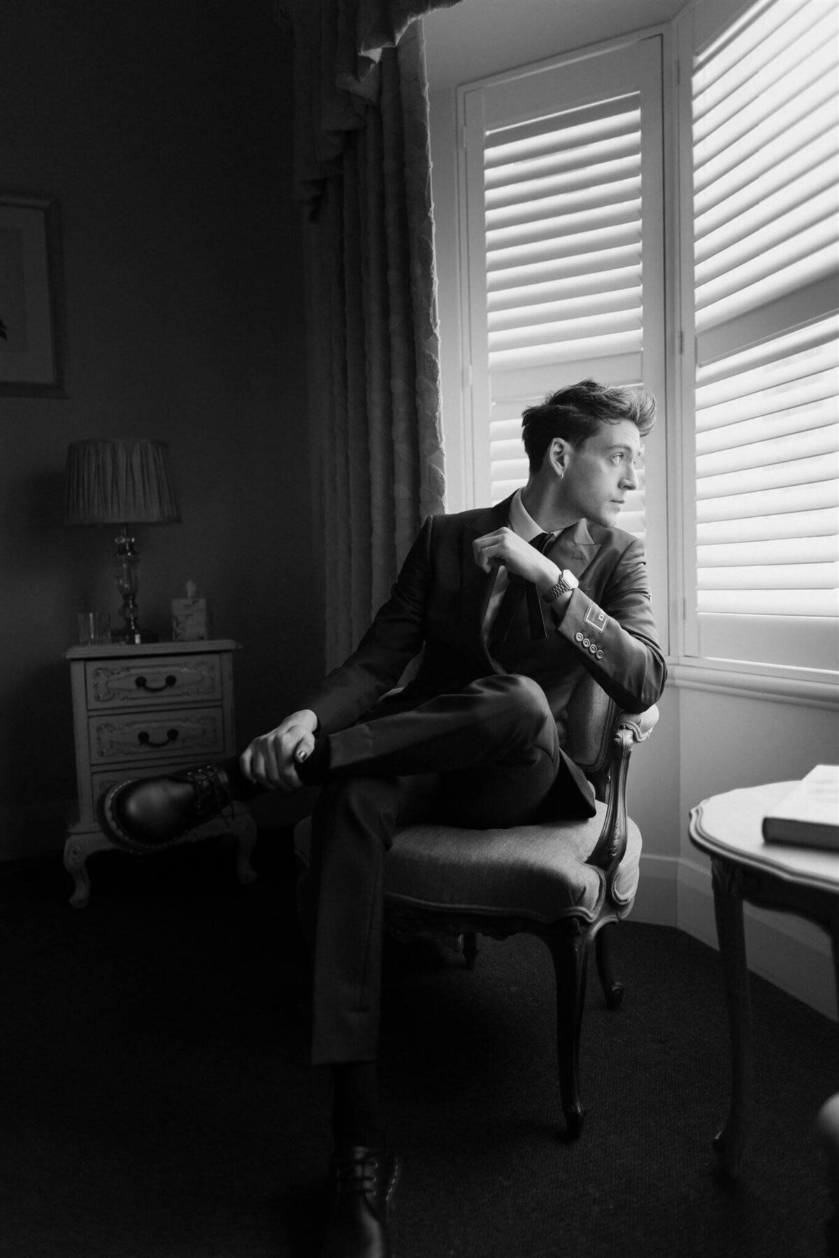 Groom on wedding day looking out a window