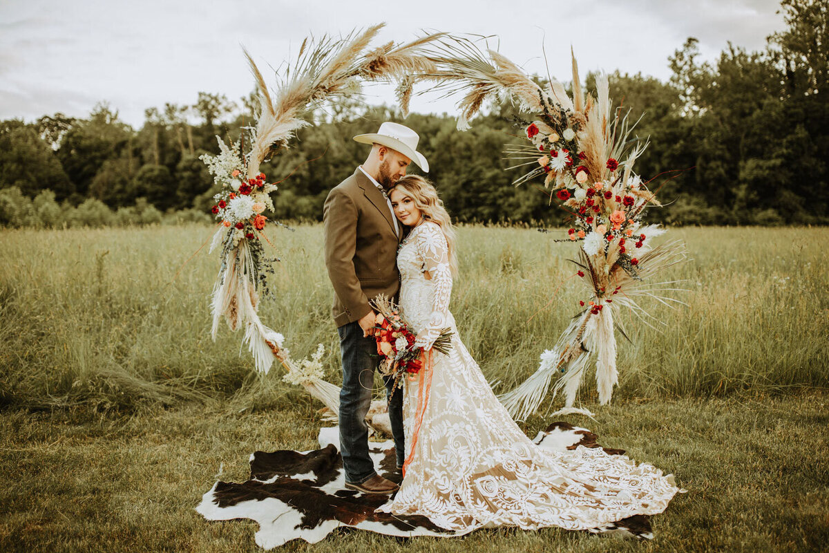 Bride and groom framed by a pampas grass and floral arch