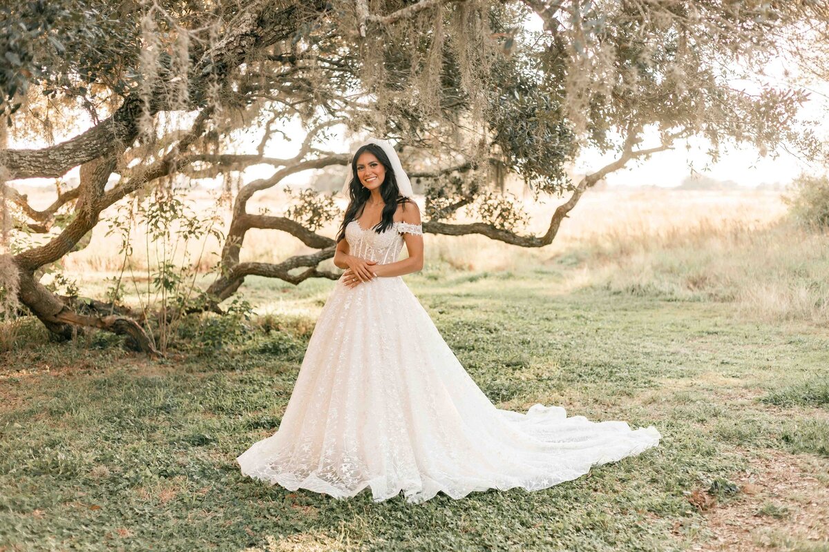 bride stands under mossy trees at Brazos bend park for Ally's Photography.