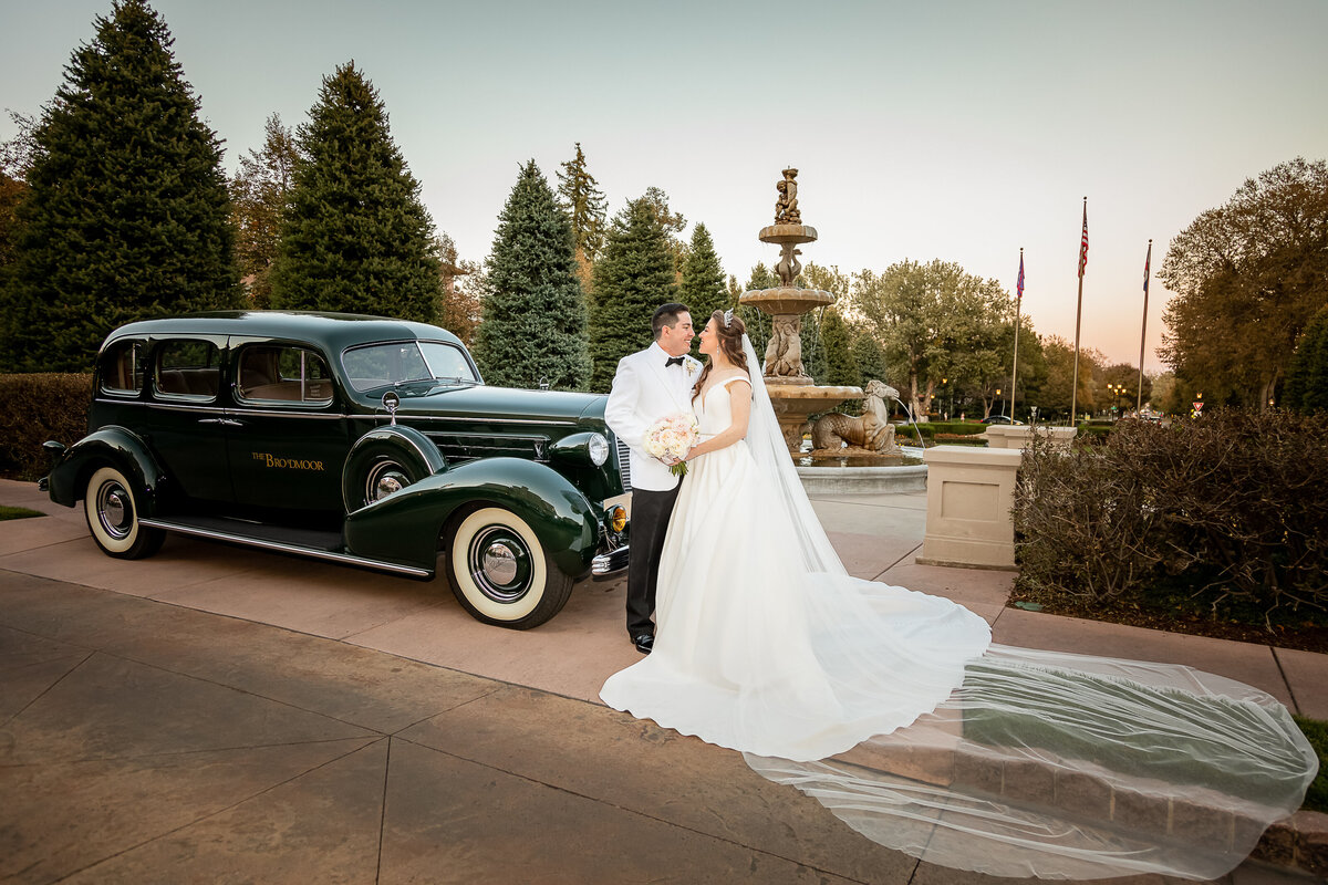 A Bride and Groom Pose with the Classic Car at the Broadmoor Hotel, Colorado