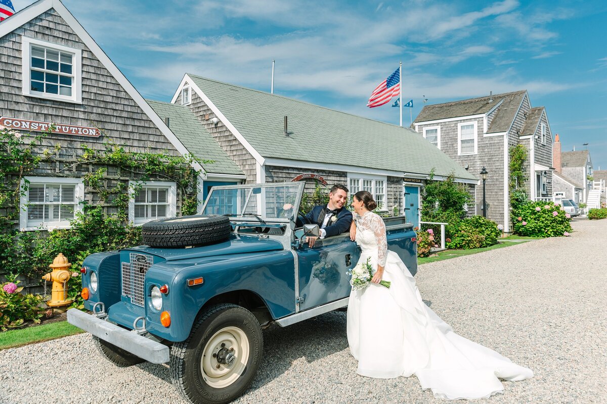 groom sits in old vintage jeep while bride leans over and kisses him