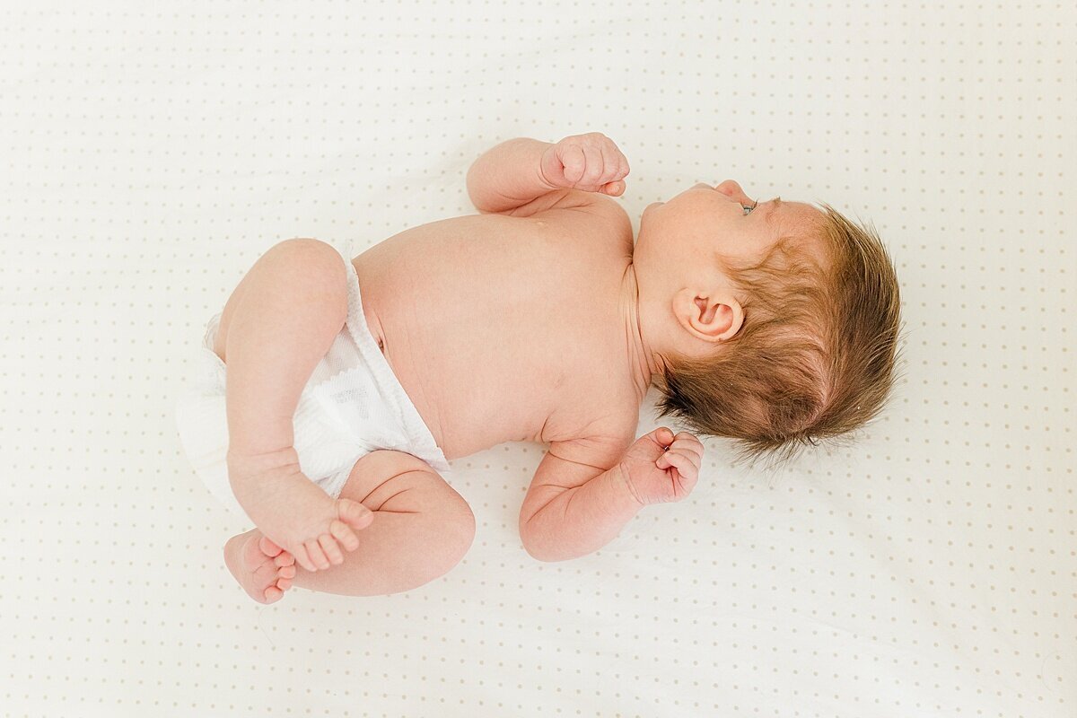 baby lays on bed during in home newborn photo session with Sara Sniderman Photography  in Natick Massachusetts