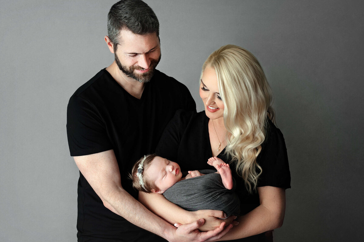 new parents holding their newborn baby at a photo shoot