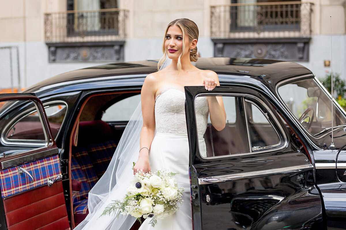bride posing in front of the omni william penn hotel in pittsburgh with a classic car