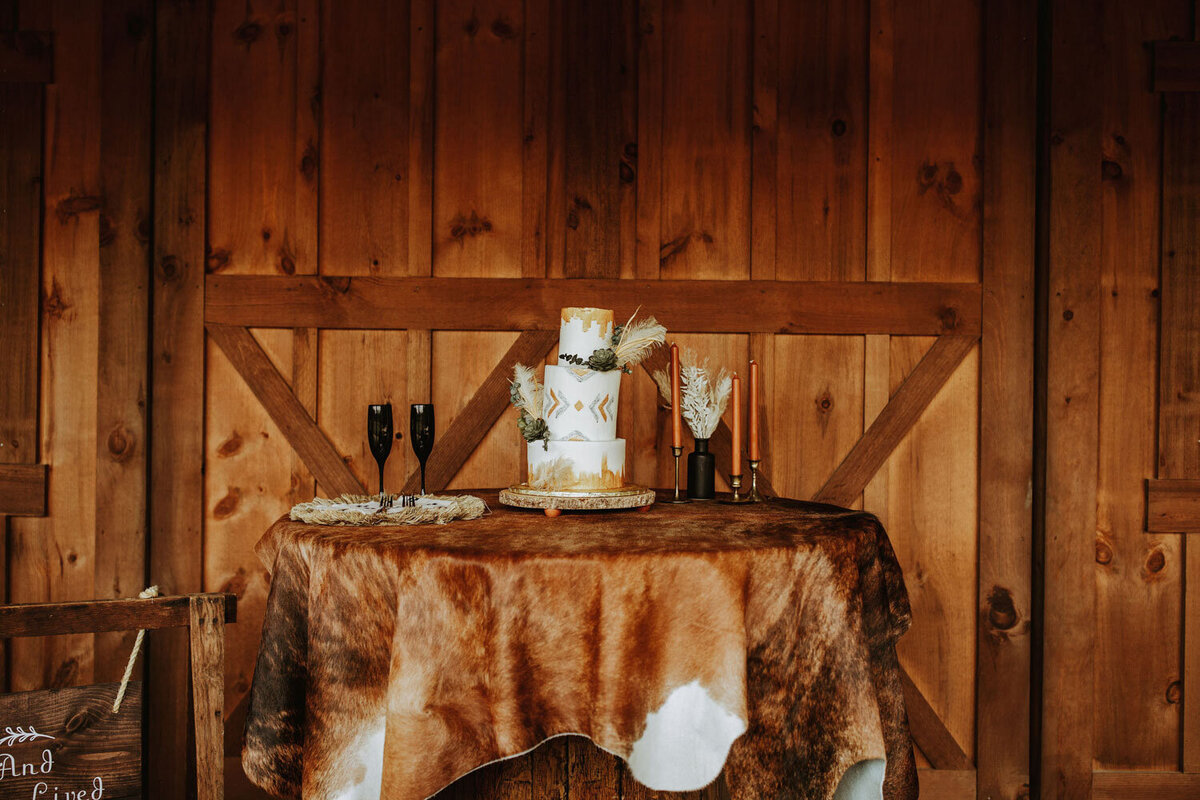 Rustic cake table with cowhide cover and two champagne flutes
