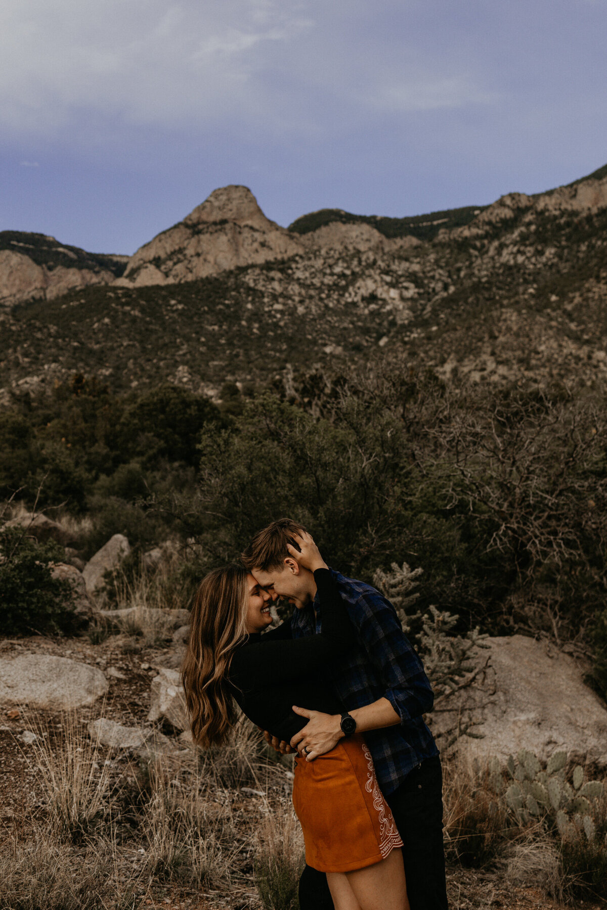 engaged couple about to kiss in front of the Sandia Mountains in Albuquerque
