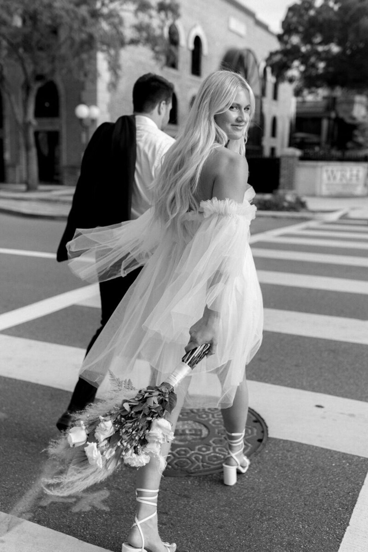 Black and white cinematic film photo with couple crossing street, taken by engagement photographer in orlando