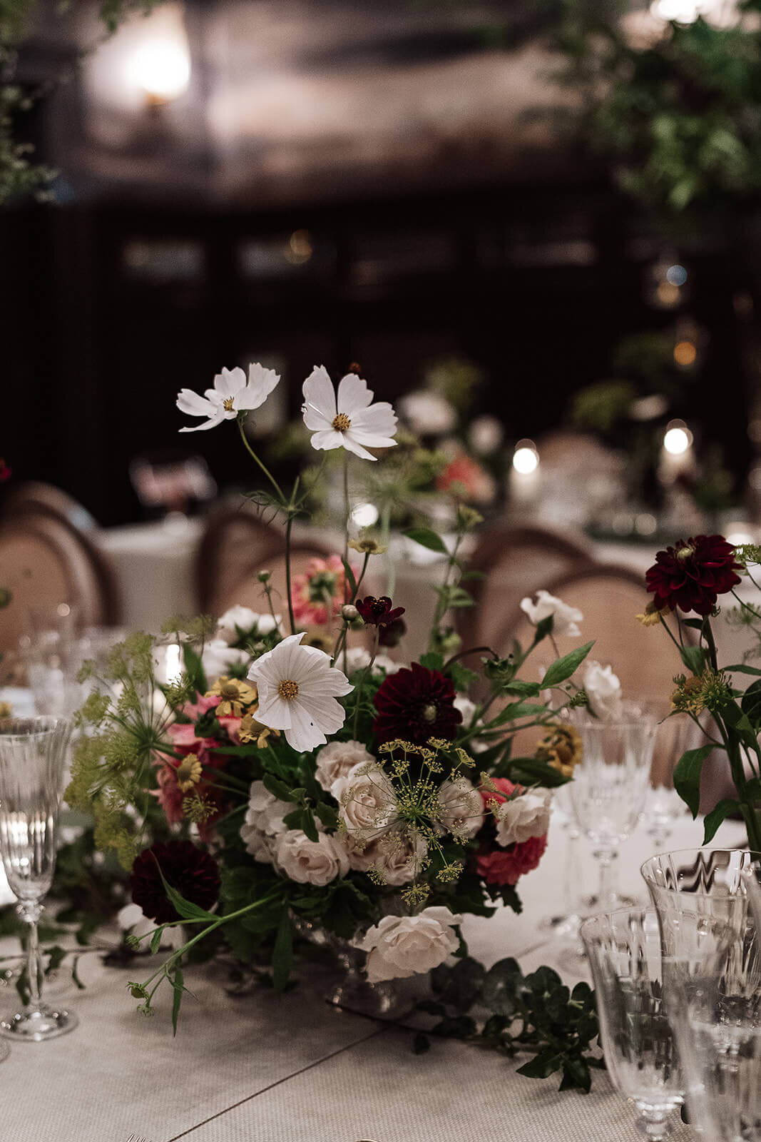 closeup of a flower arrangement featuring cosmos and dahlias on a beige table in the ballroom of the nomad London for an intimate wedding party