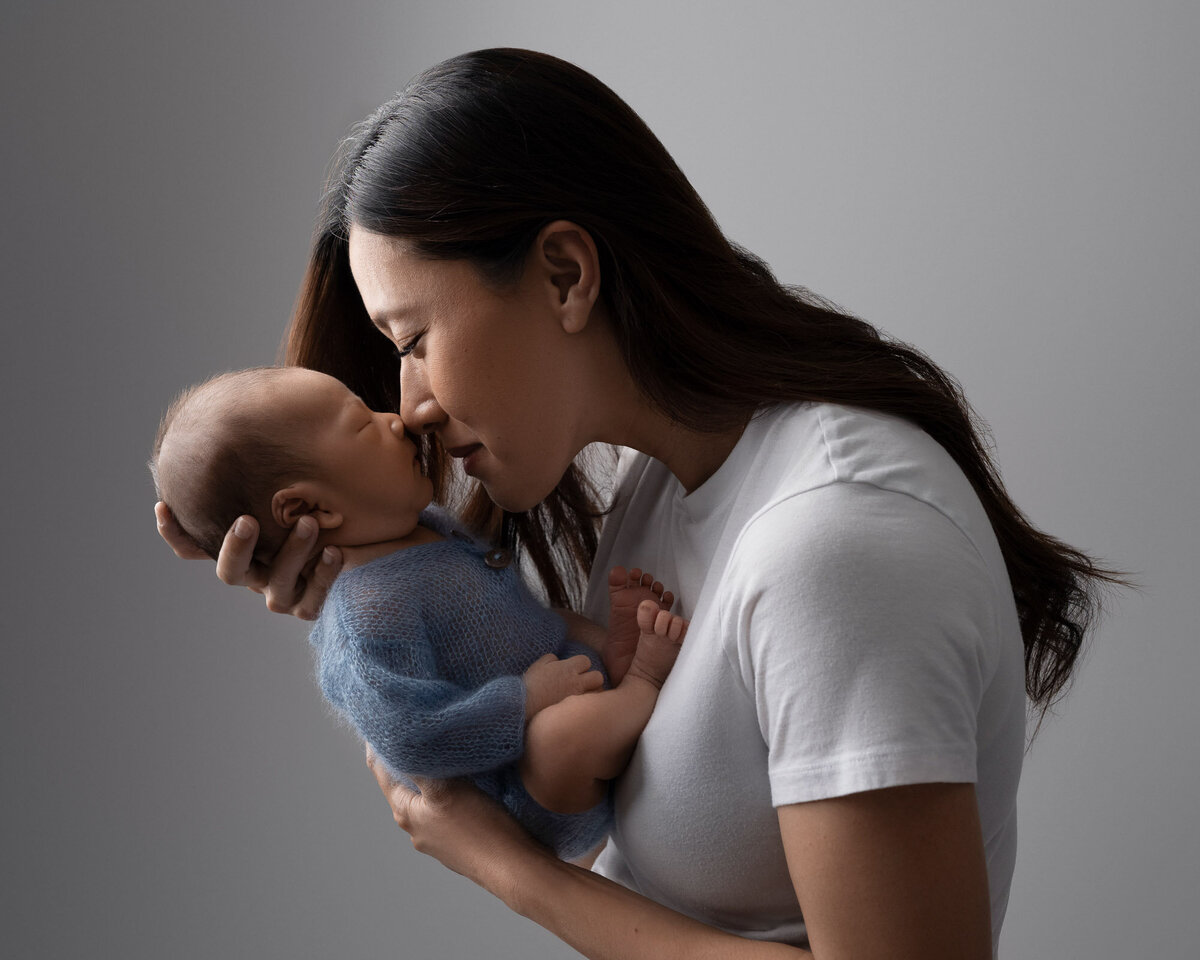 Mother kissing newborn baby tender moment Westlake family photographer
