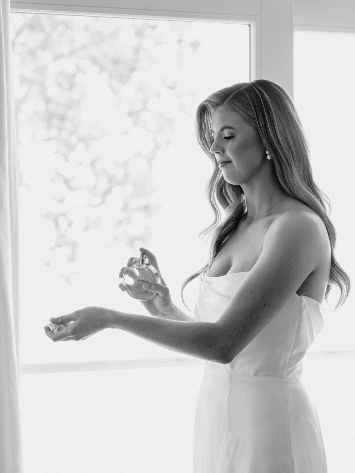 Bride applying perfume on