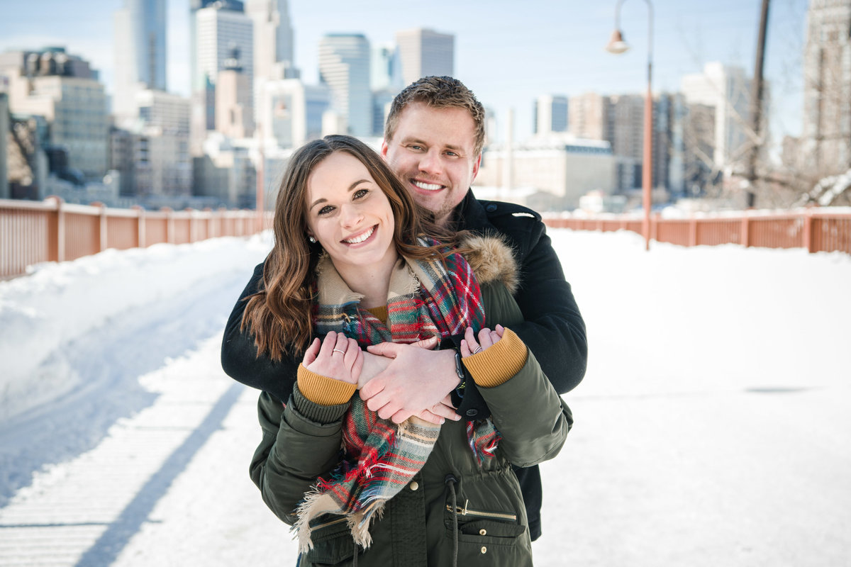 Man and woman smile on the snow covered Stone Arch Bridge in Minneapolis, Minnesota.