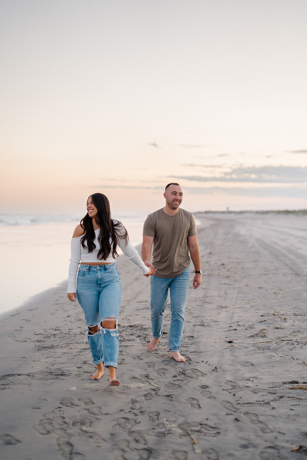 A couple holding hands and walking on the beach in Avalon, NJ