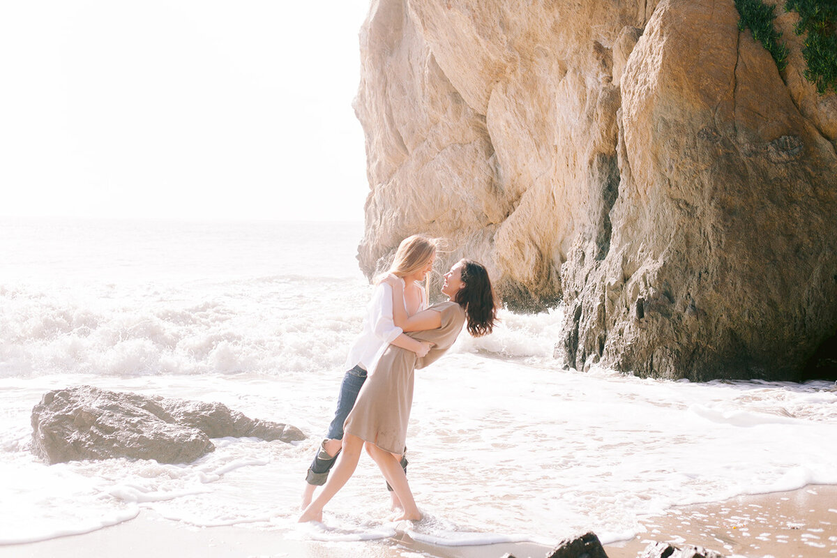 Two women embrace on El Matador Beach in  Malibu california
