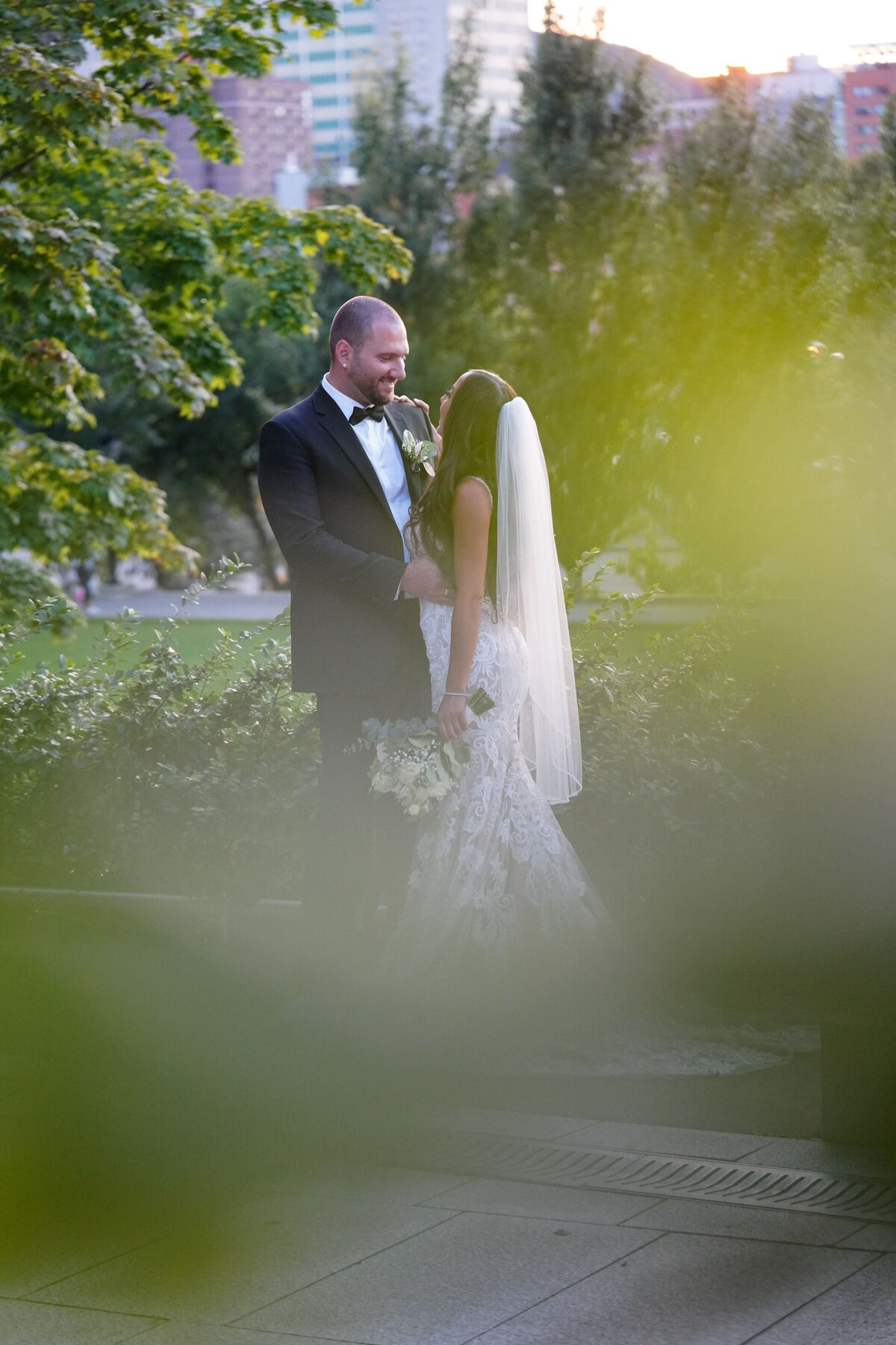 The bride and groom pose lovingly in a picturesque park setting. Surrounded by lush greenery and tranquil nature, their intimate embrace highlights their joy and connection, creating a serene and romantic portrait of their wedding day.