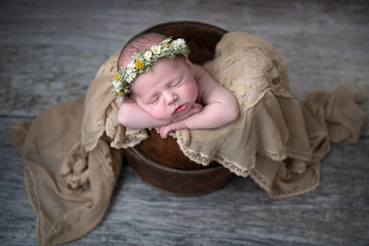 newborn girl in bucket wearing flower crown