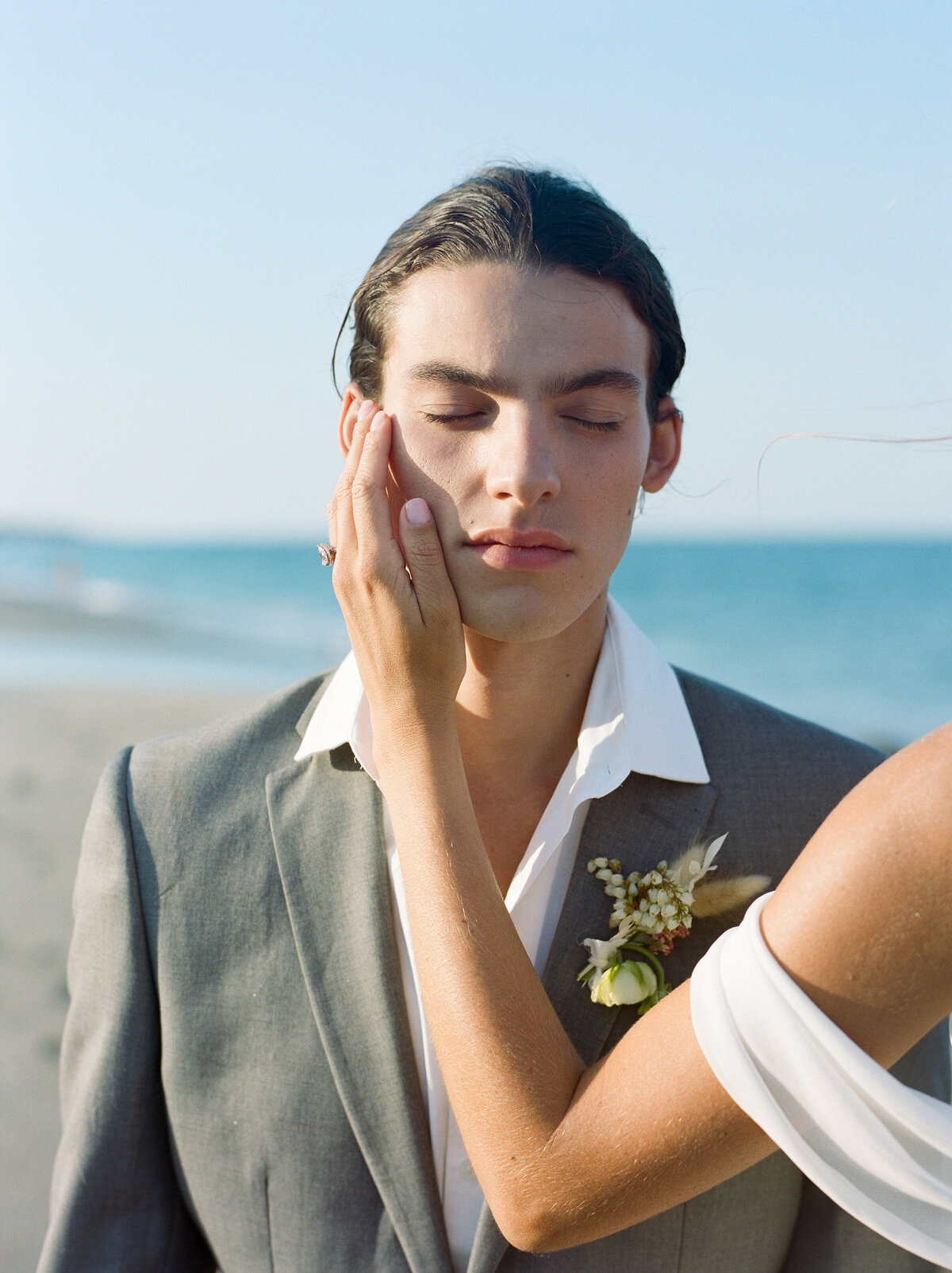 Bride brushes grooms face with a show stealing boutineare.