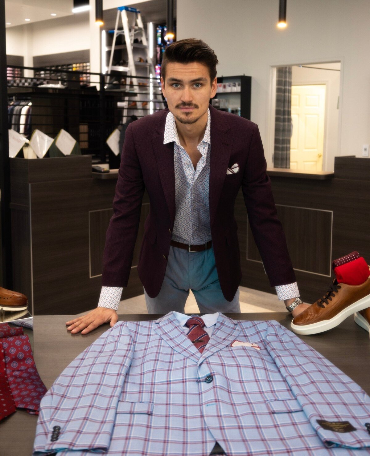 A man showing off men’s business formal fashion trends on a table in a clothing store