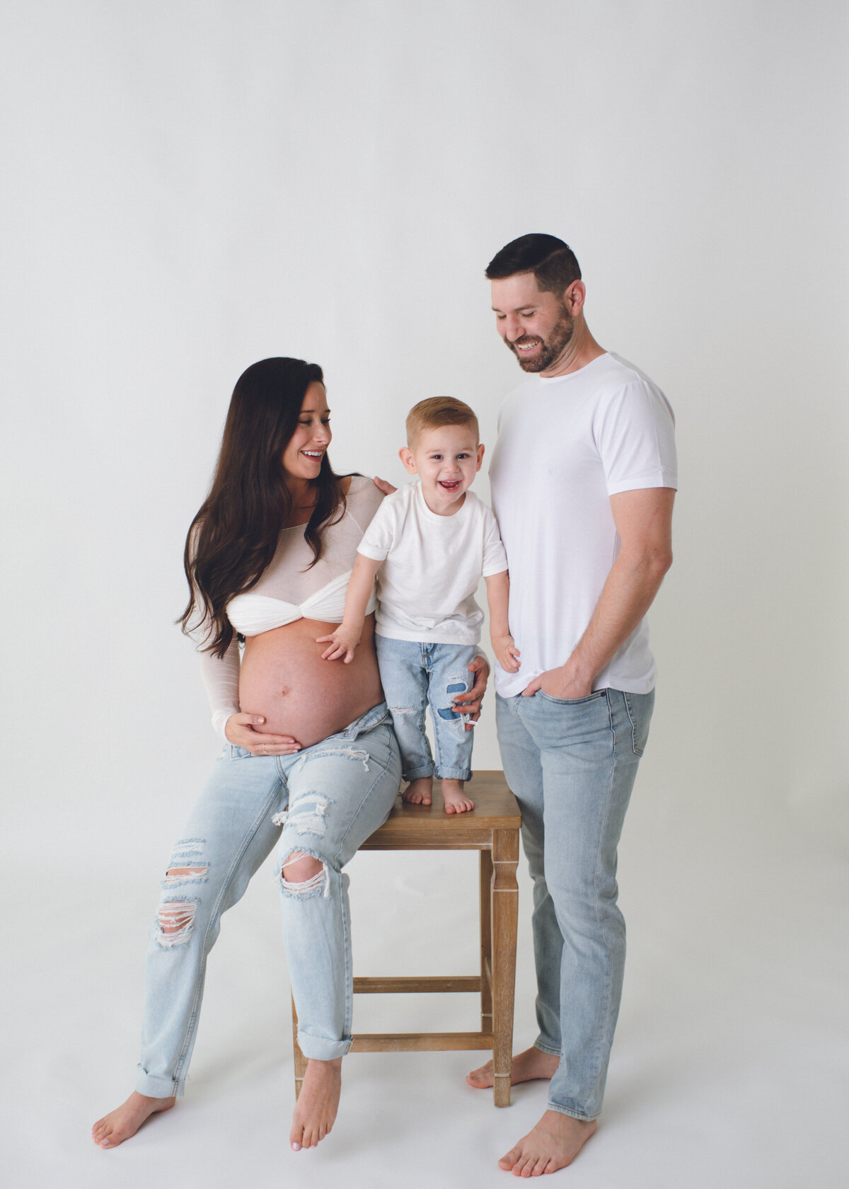 mom and dad with toddler celebrating second pregnancy with pictures