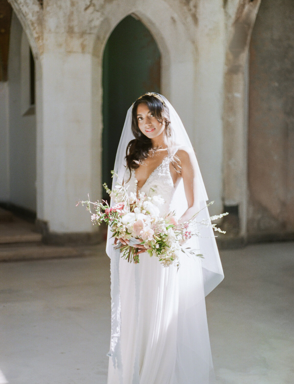 Indian bride in sunlight, colorful bouquet, Greece ruins wedding venue