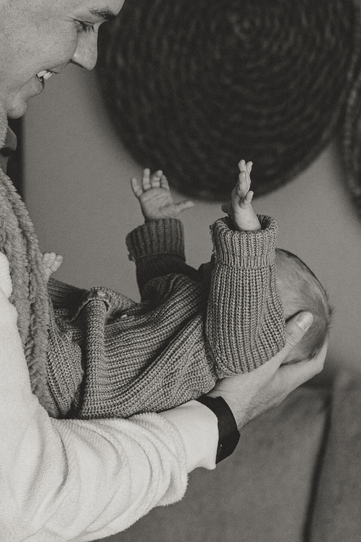 Longmont newborn reaching up towards dad while dad is holding newborn
