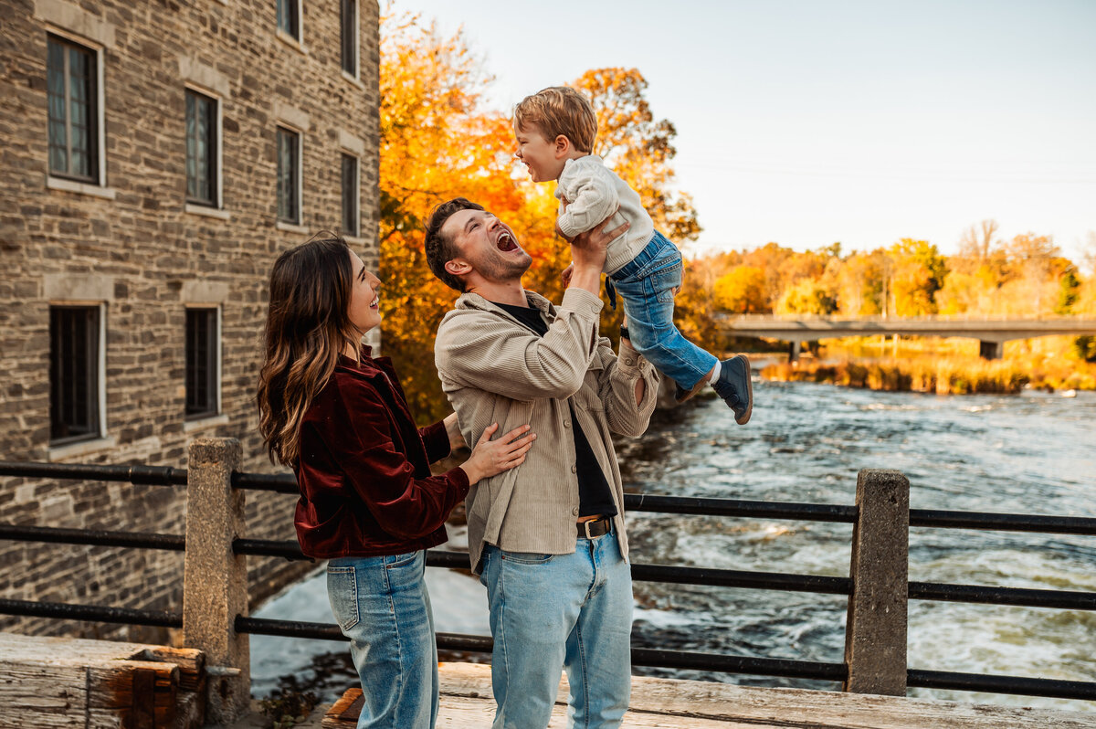 Couple embracing during Ottawa fall mini session near stone architecture with colourful leaves.