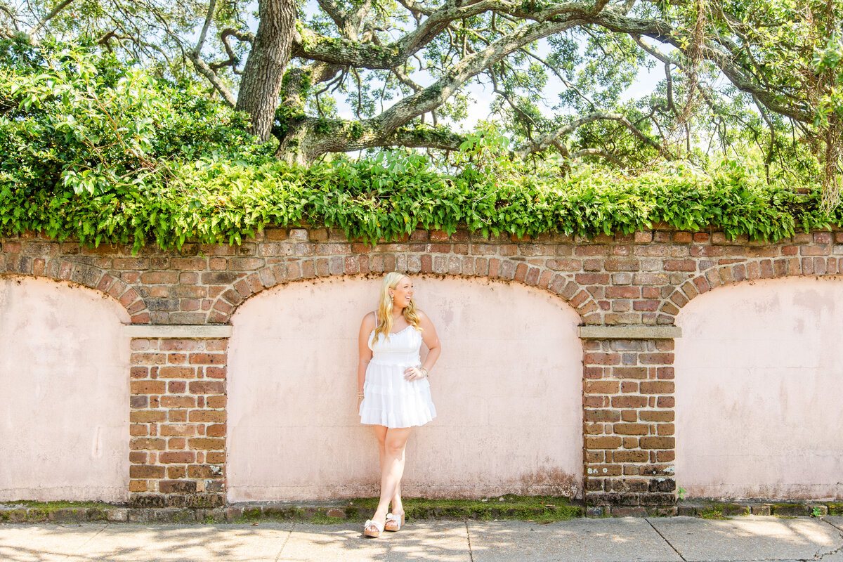 senior high school girl posing in front of pink and brick structure