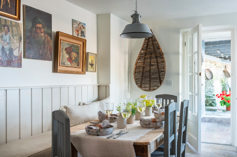 Dining table in coastal home featuring paintings on the wall