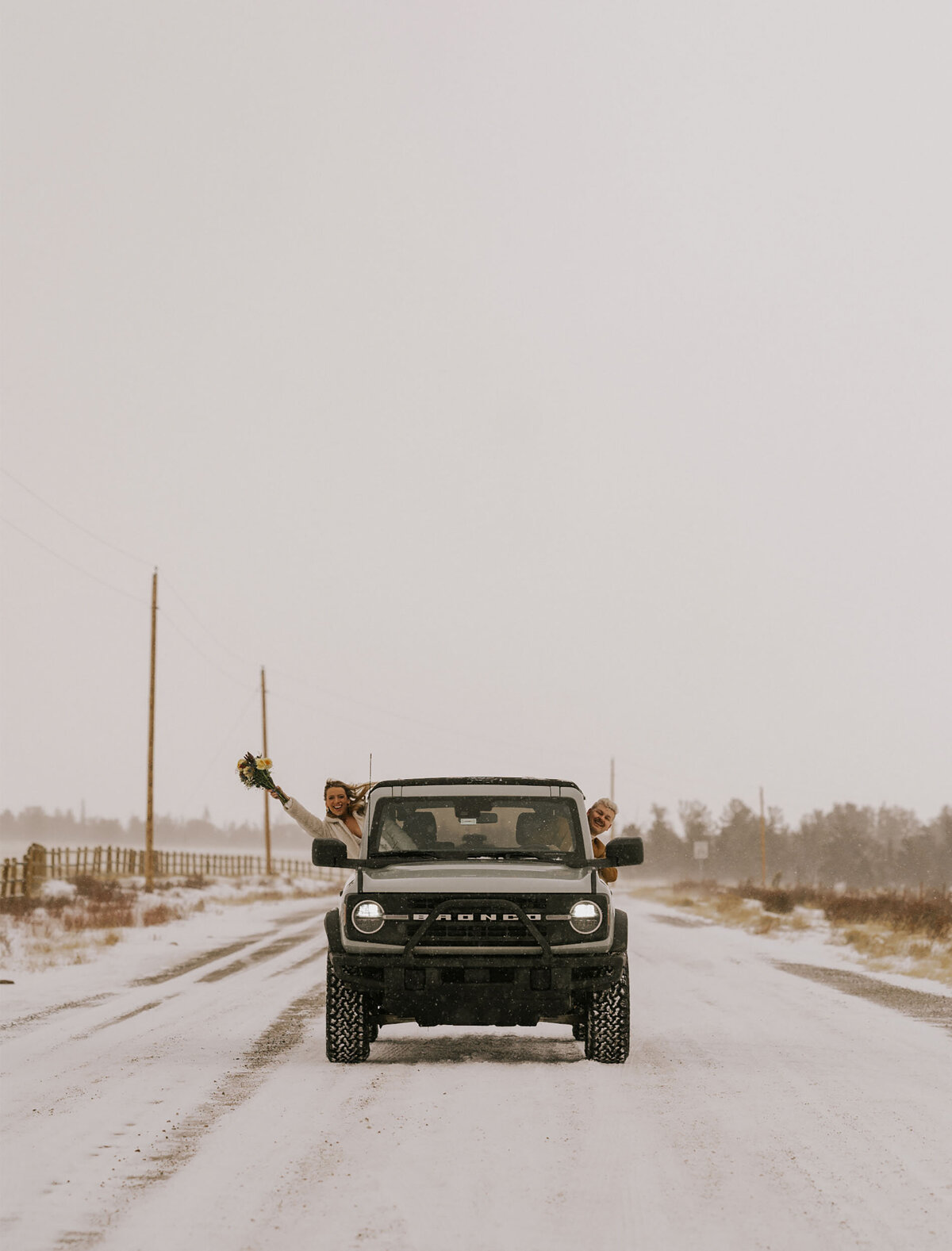 bride and groom drive their jeep bronco along a snowy road in Bend, Oregon