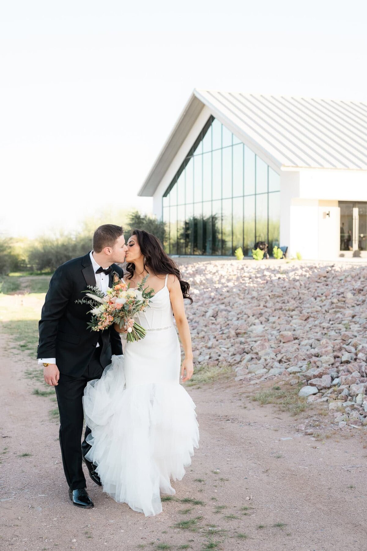 Bride and groom walking and kissing in front of Desert View Weddings.