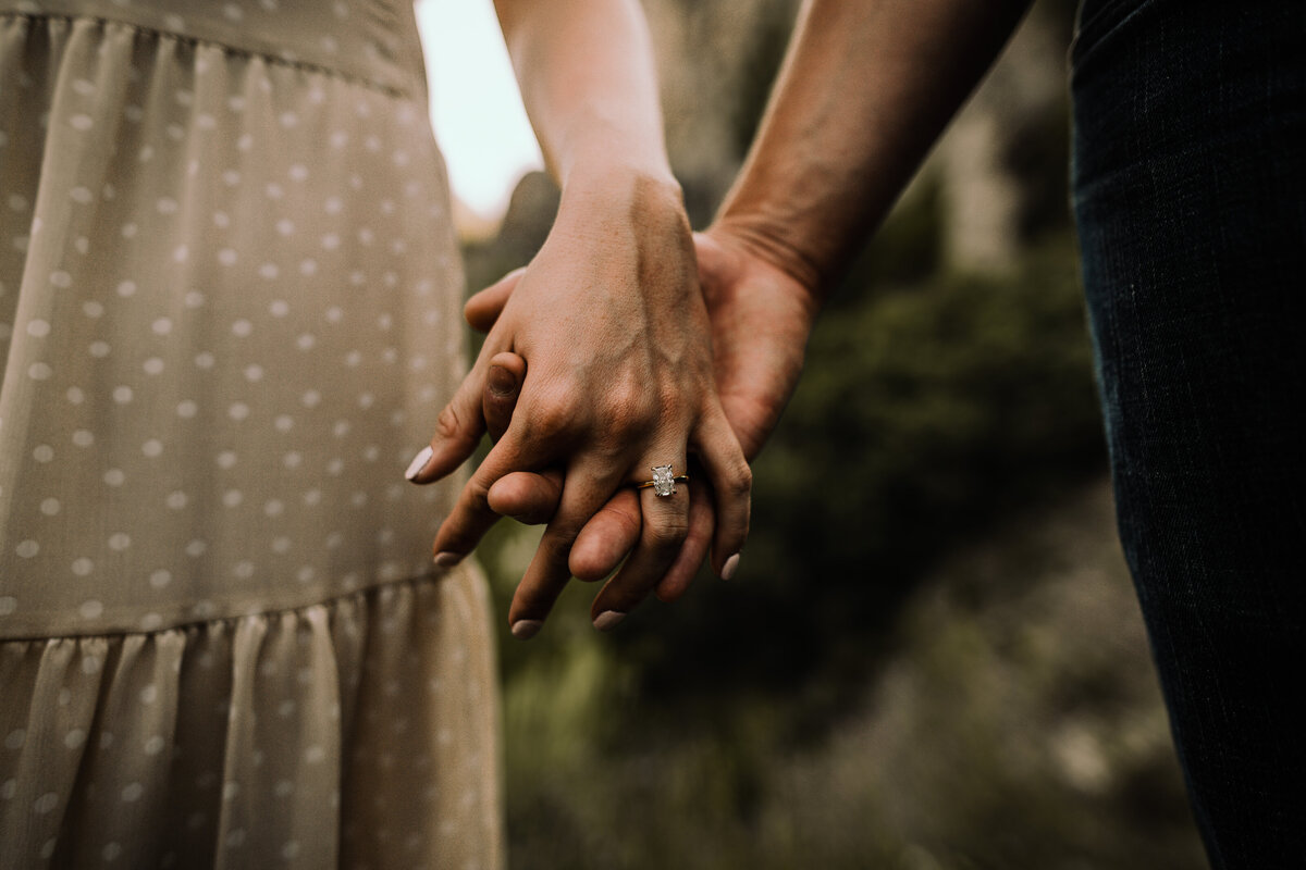 close up shot of bride and groom holding hands showing engagement ring