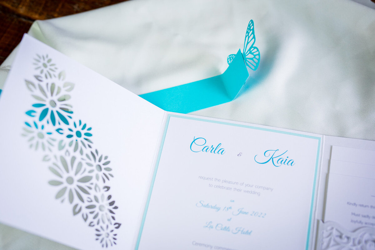 Handcrafted wedding invitation in white and turquoise with unique butterfly clasp
