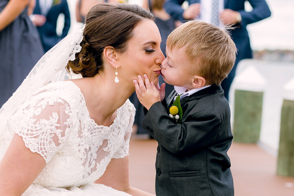 A bride kisses her son on the dock.
