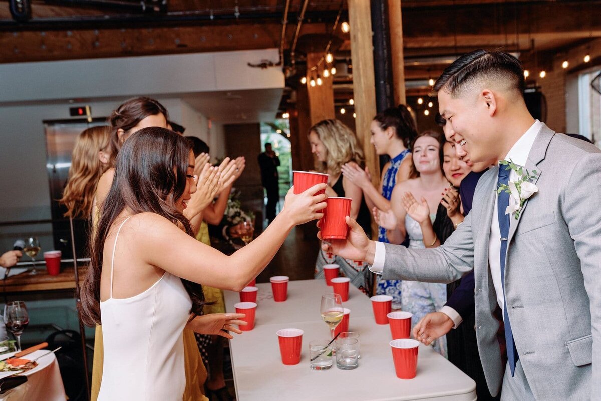 Bride and Groom surprise guests play flip cup in between speeches reception games at hotel ocho toronto wedding jacqueline james photography
