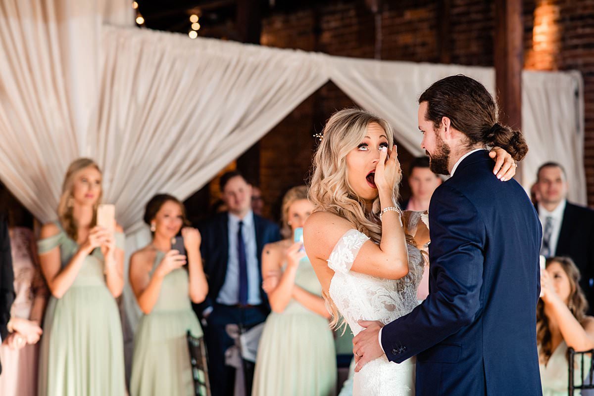 Groom surprises bride with song recorded just for her for their first dance, candid photo of her surprise and emotions