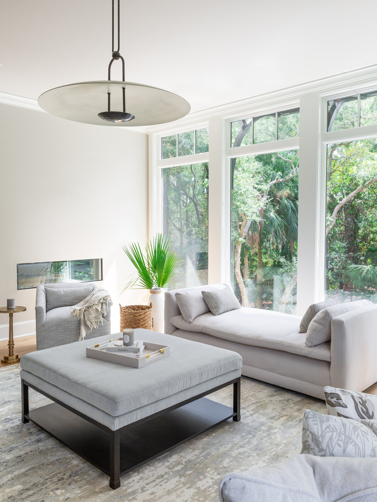 Elegant living space in Kiawah Island, SC, with plush seating, a chic ottoman, and large windows.